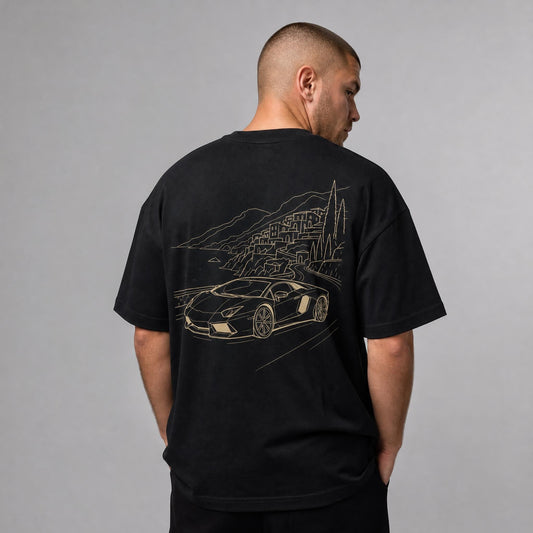 Rücken des schwarzen Amalfi Vibes Oversized T-Shirts von CLUTCHO: große Champagner-Line-Art eines italienischen Supersportwagens über der Amalfiküste.