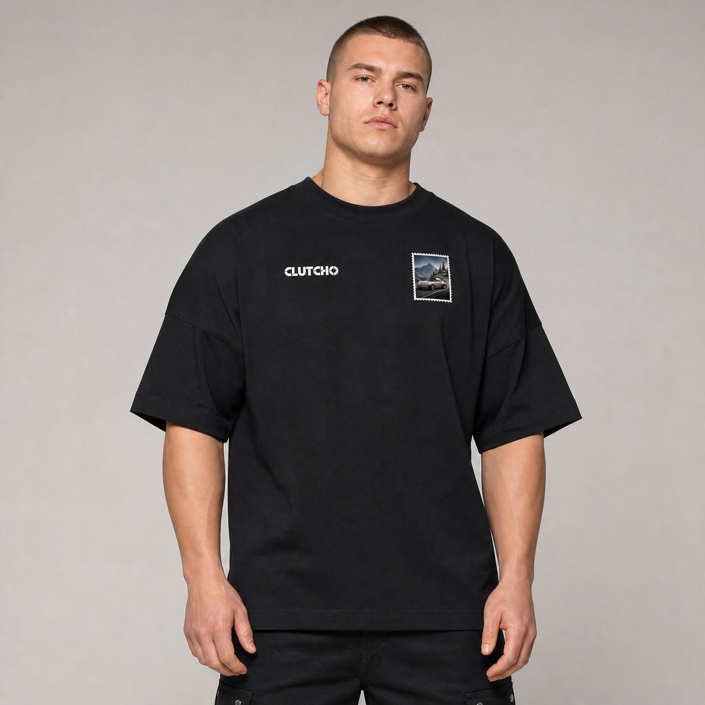 Schwarzes CLUTCHO Alpenpass Oversized T-Shirt Herren, Front-Briefmarke mit klassischem Heckmotor-Sportwagen auf einem Alpenpass.