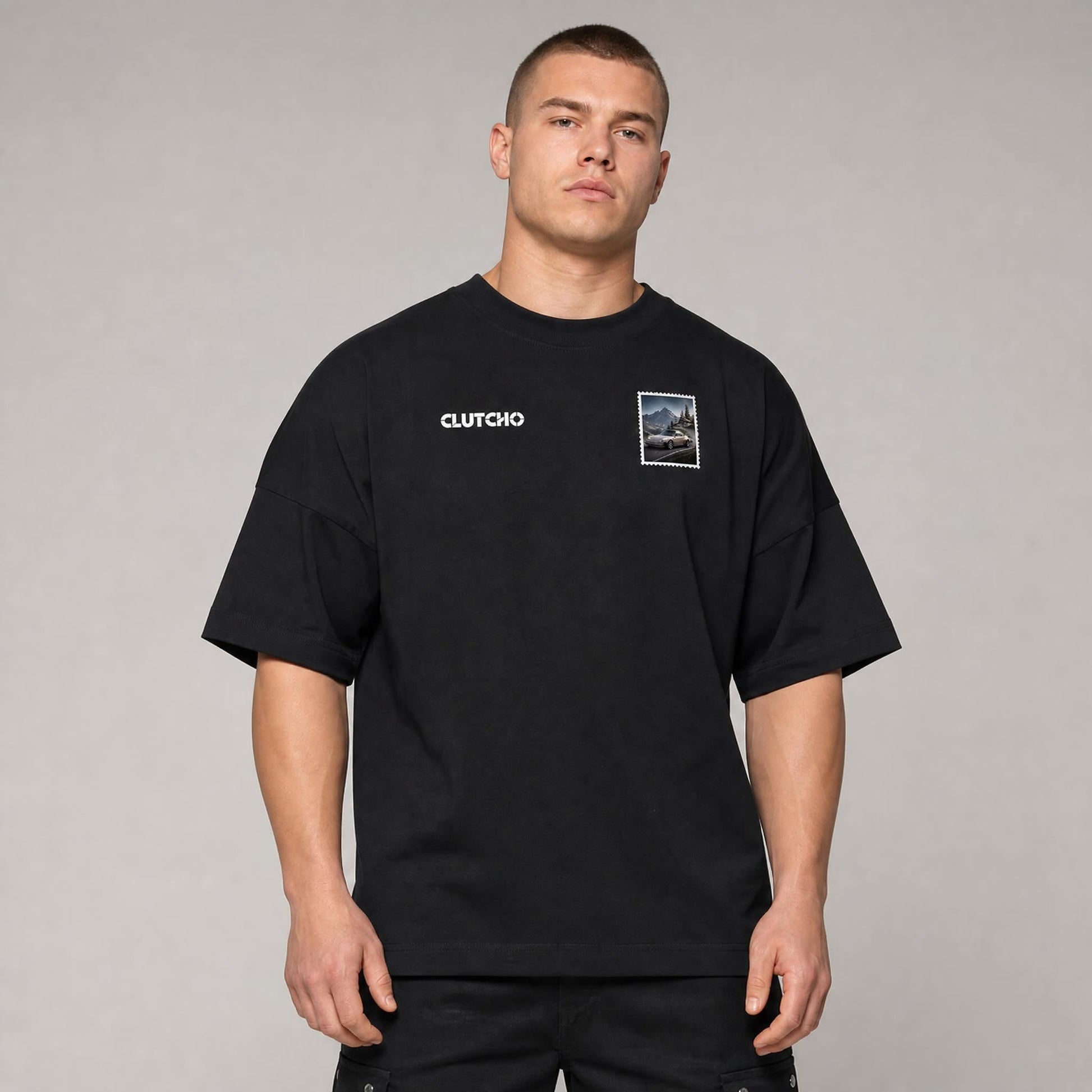 Schwarzes CLUTCHO Alpenpass Oversized T-Shirt Herren, Front-Briefmarke mit klassischem Heckmotor-Sportwagen auf einem Alpenpass.