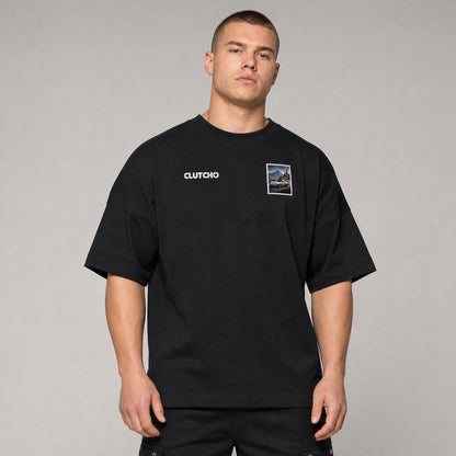 Schwarzes CLUTCHO Alpenpass Oversized T-Shirt Herren, Front-Briefmarke mit klassischem Heckmotor-Sportwagen auf einem Alpenpass.