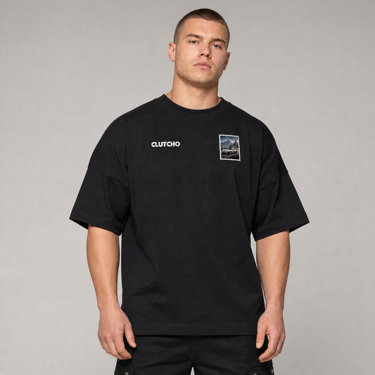 Schwarzes CLUTCHO Alpenpass Oversized T-Shirt Herren, Front-Briefmarke mit klassischem Heckmotor-Sportwagen auf einem Alpenpass.