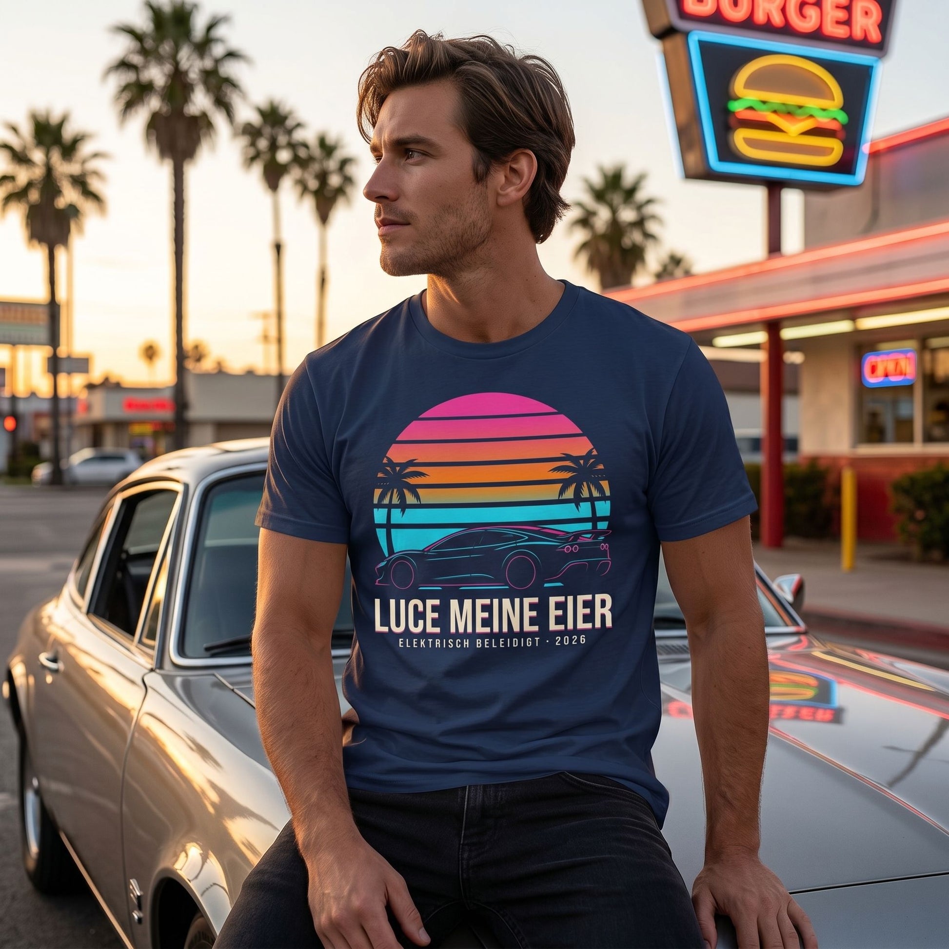 Side view of the T-shirt on a model seated on a vintage car hood, highlighting the colorful print at sunset.