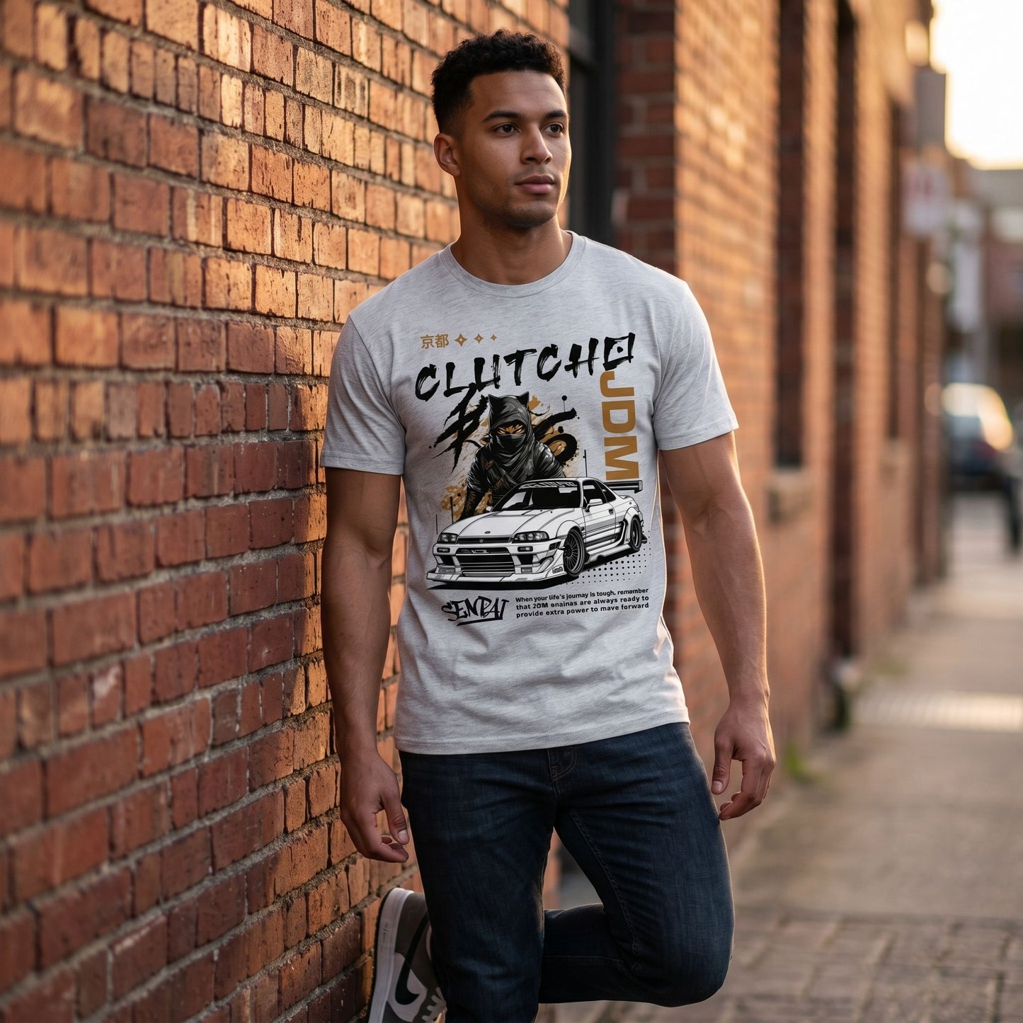 Full-body shot of model in grey CLUTCHO Senpai JDM T-Shirt in urban street environment during golden hour.