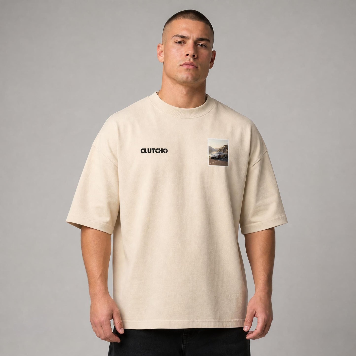 Beiges CLUTCHO Fjord Oversized T-Shirt Herren, Front-Briefmarke mit Hypercar an einem nordischen Fjord.