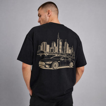 Rücken des schwarzen Frankfurt Skyline Oversized T-Shirts von CLUTCHO: große Champagner-Line-Art eines deutschen Sportwagens vor der Frankfurter Skyline.
