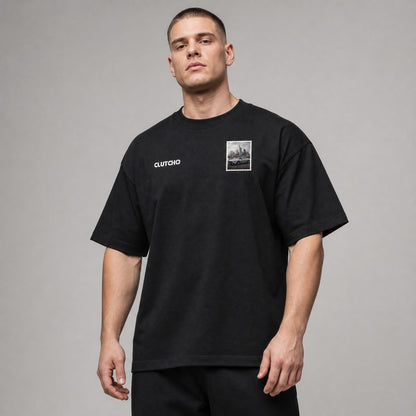 Schwarzes CLUTCHO Frankfurt Skyline Oversized T-Shirt Herren, Front-Briefmarke mit deutschem Sportwagen vor der Frankfurter Skyline.