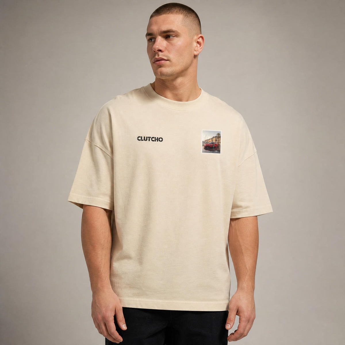 Beiges CLUTCHO Monaco Vibes Oversized T-Shirt Herren, Front-Briefmarke mit italienischem Supersportwagen an der Hafenpromenade von Monaco.