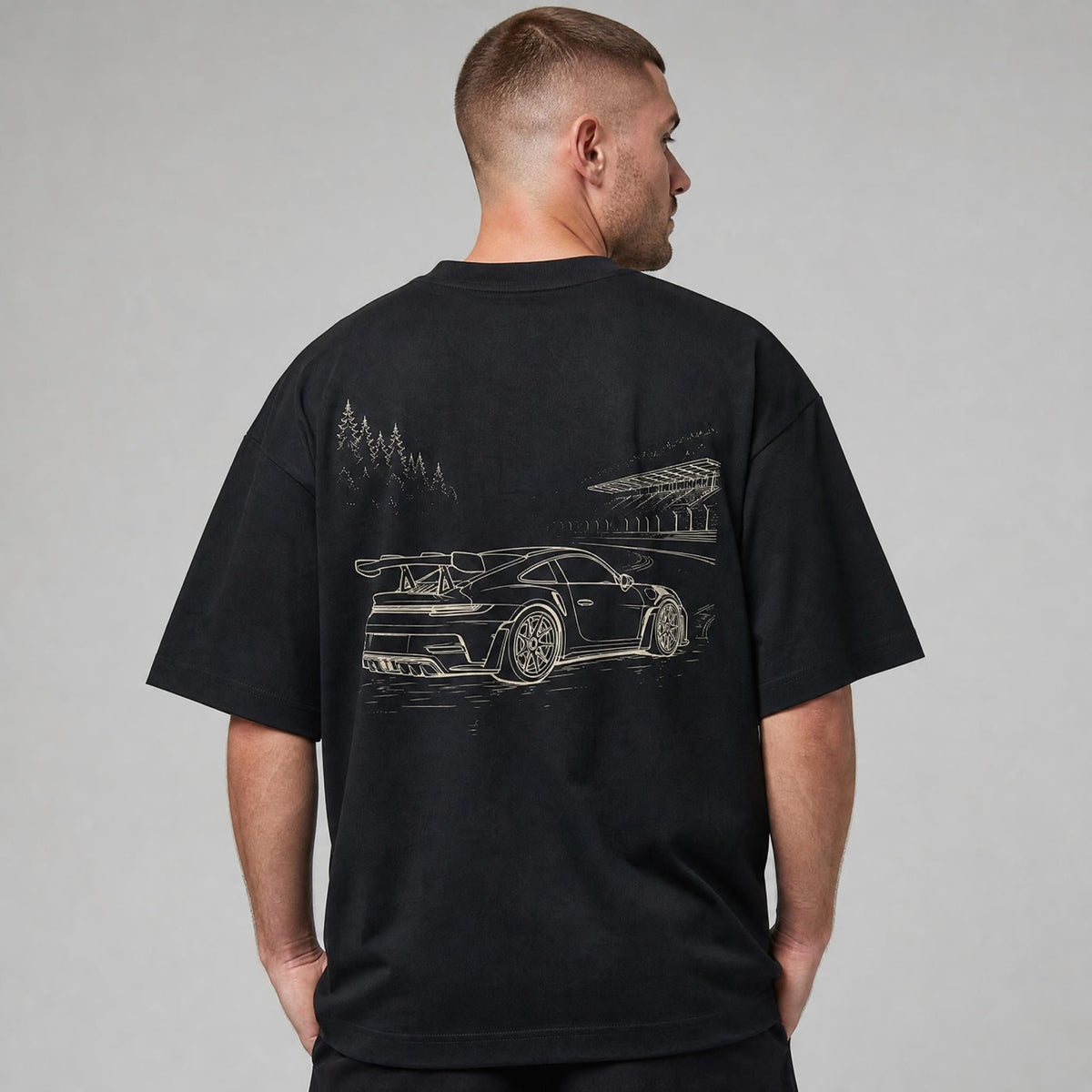 Rücken des schwarzen Nürburgring Oversized T-Shirts von CLUTCHO: große Champagner-Line-Art eines deutschen Sportwagens auf der Nordschleife.