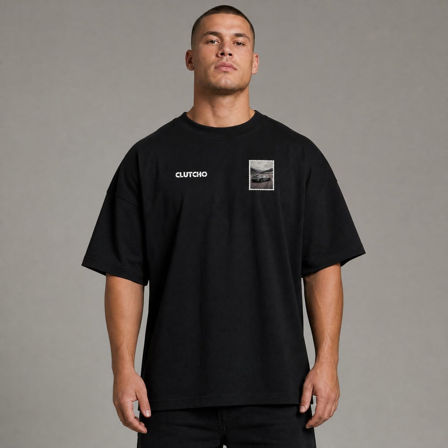 Schwarzes CLUTCHO Nürburgring Oversized T-Shirt Herren, Front-Briefmarke mit deutschem Sportwagen auf der Nordschleife.