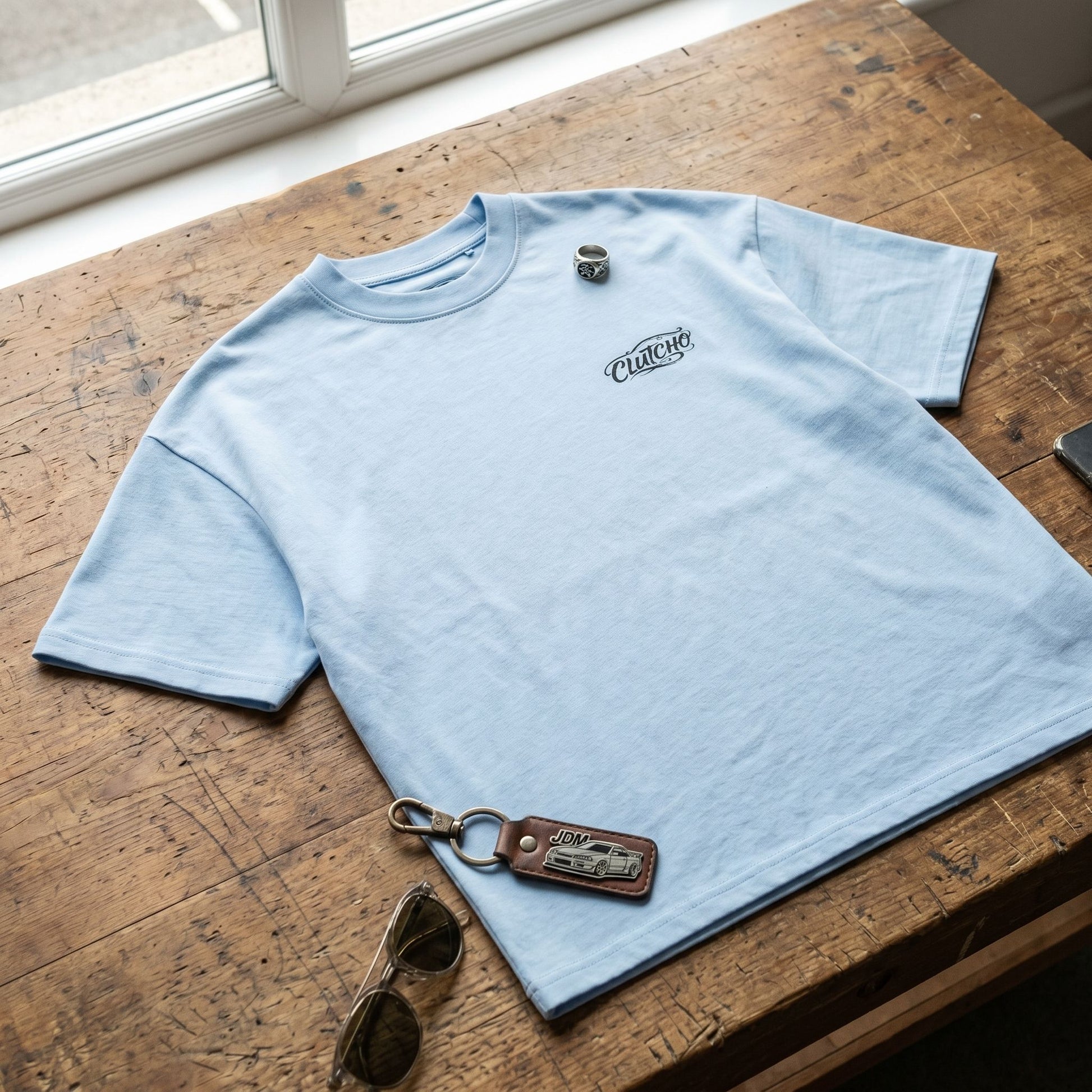 Overhead view of Tokyo Night Drive Oversized Shirt laid on textured wooden table with casual streetwear accessories.
