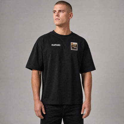 Schwarzes CLUTCHO Toskana Vibes Oversized T-Shirt Herren, Front-Briefmarke mit italienischem Supersportwagen auf einer Toskana-Landstraße.
